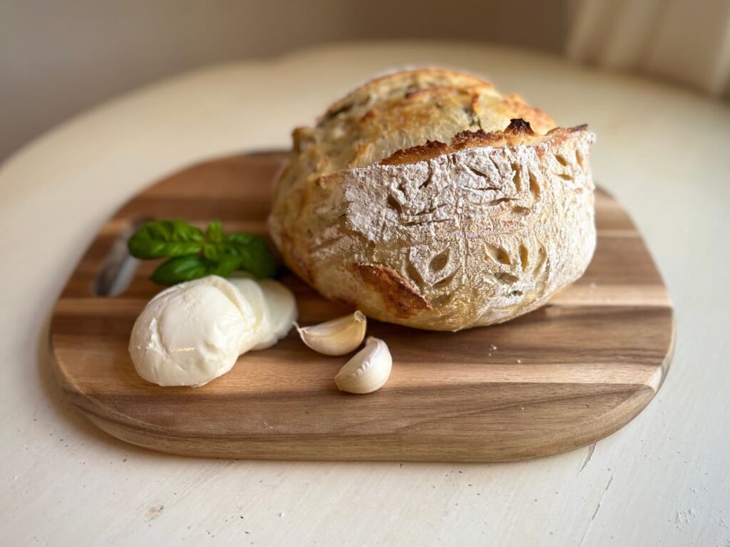 Garlic, Basil, Mozzarella artisan sourdough bread on a cutting board