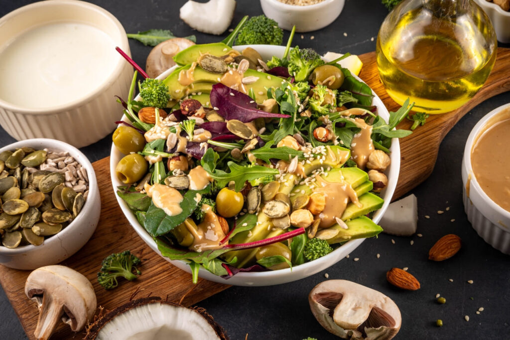 Jar of peanut butter salad dressing beside fresh greens.