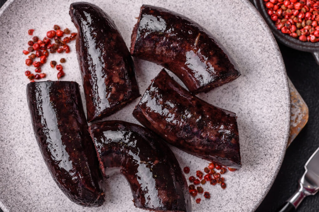 Delicious black blood sausage or black pudding with spices and herbs grilled on a black concrete background