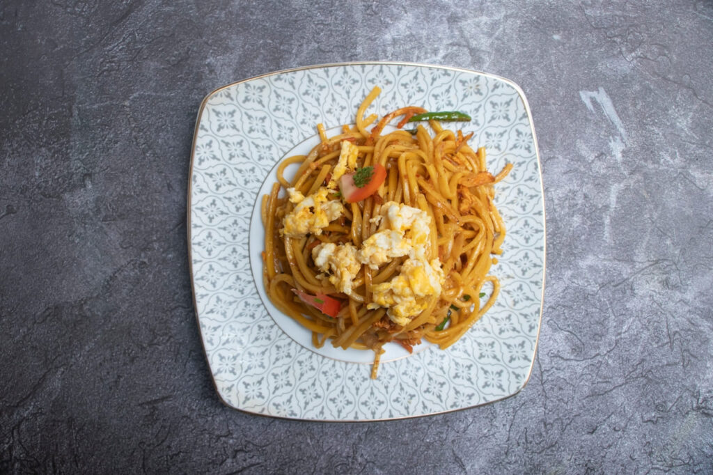 Stir Fried Egg Noodles with Vegetables and Scrambled Egg, Served on a Plate top view of Chinese food