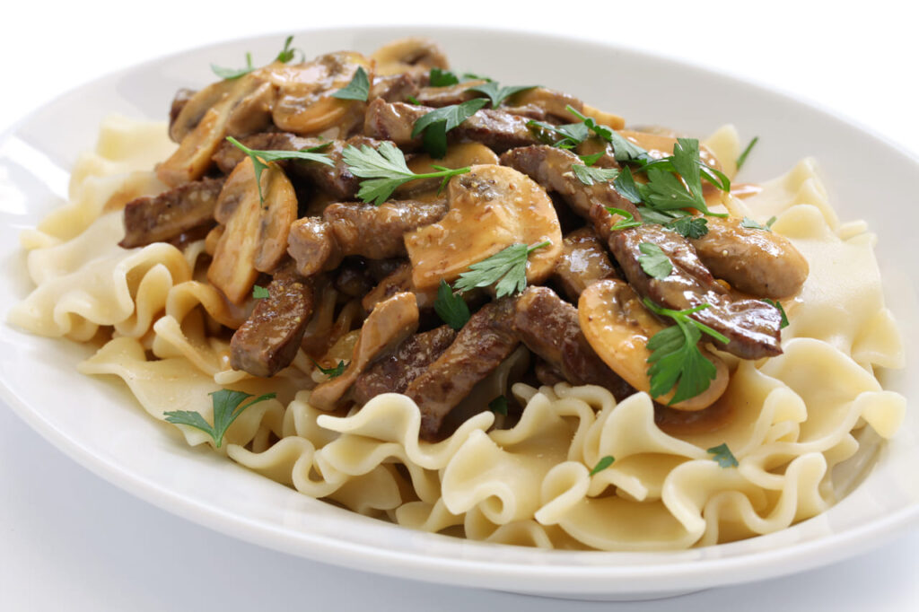 Creamy beef stroganoff served over buttered egg noodles with a sprinkle of parsley.