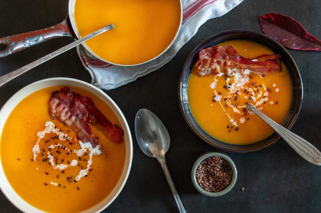 Steaming bowl of creamy butternut squash soup with a swirl of cream and pumpkin seeds.