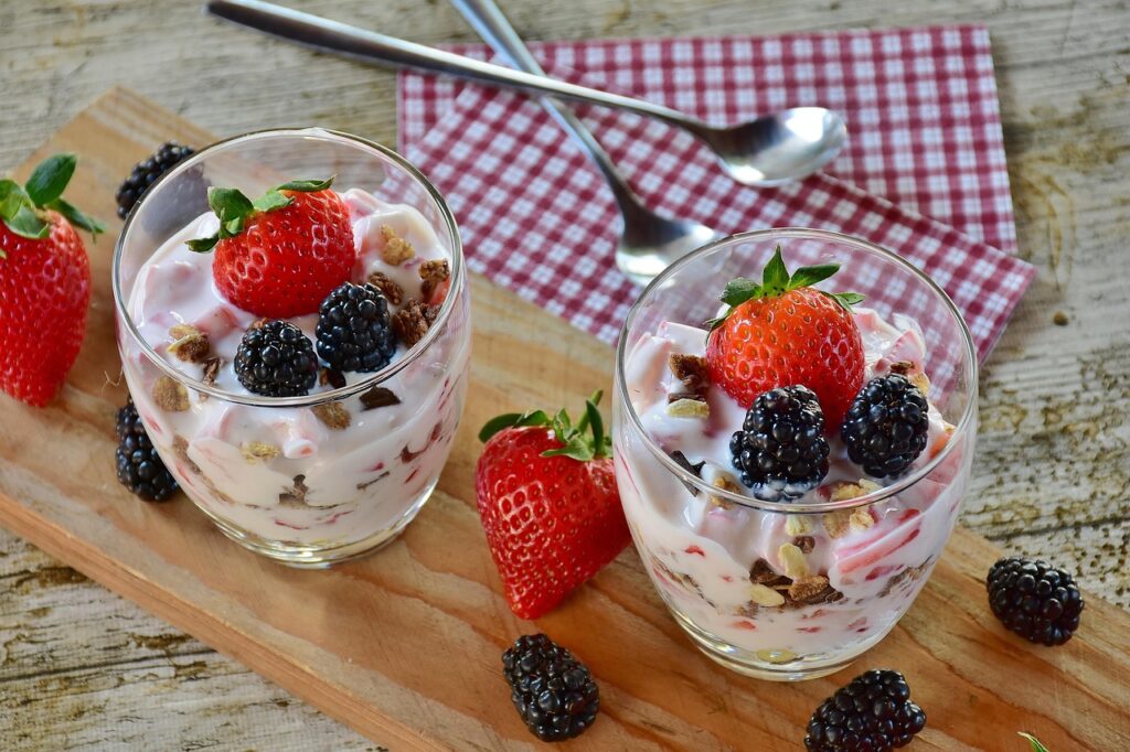 A bowl of plain yogurt topped with fresh berries and honey.