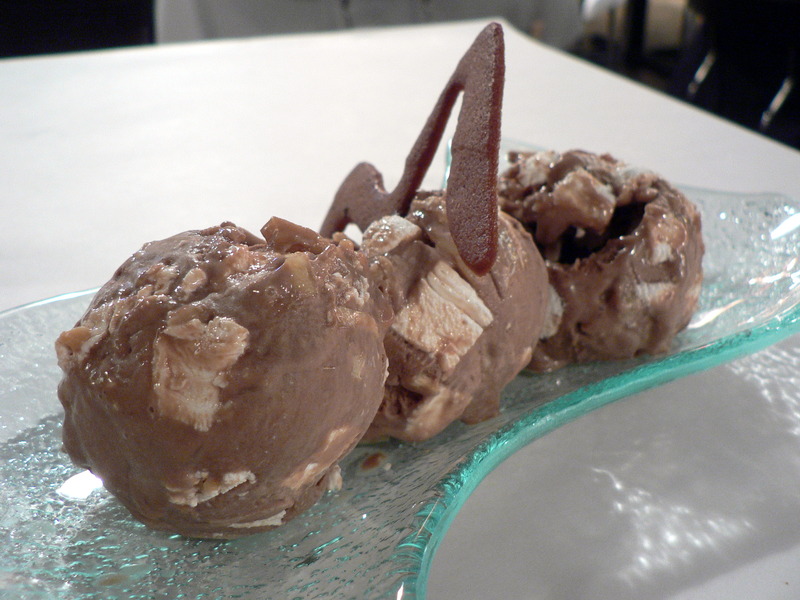 Three scoops of rocky road ice cream, with a chocolate cookie
