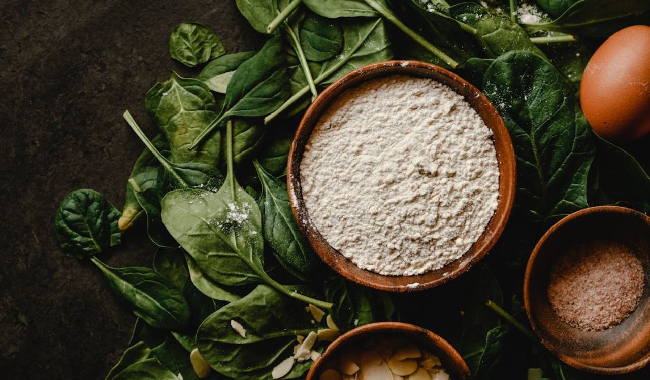 White Flour in the Wooden Bowl on the Green Leaves